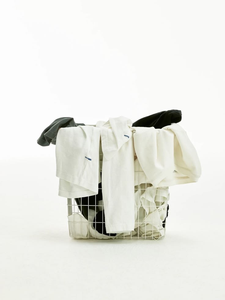 A wire laundry basket piled with white and dark clothes